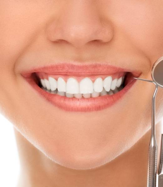 A woman is smiling while being at the dentist